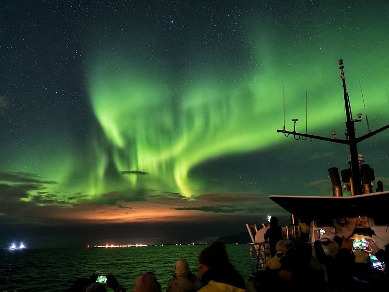 Aurora curtains seen from the deck of a boat, the mast on the right