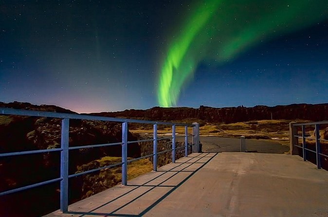 An aurora rising over a railed viewing platform in the dark